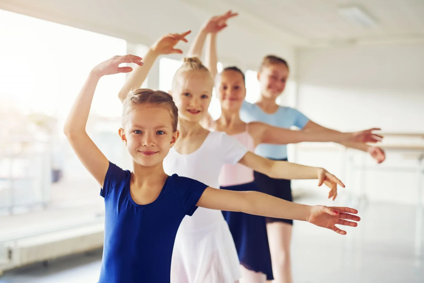 Vier Mädchen üben eine Ballettfigur im Tanzsaal